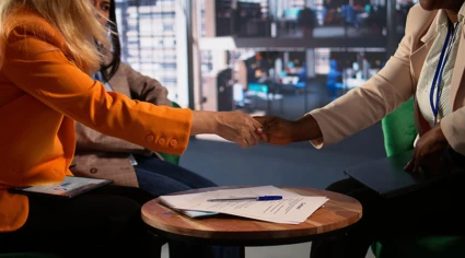 Två kvinnor skakar hand med varandra