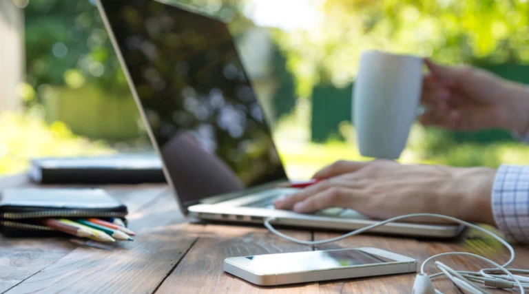 Man jobbar vid en laptop ute i naturen