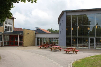 Dackeskolan med asfalterad skolgård med utplacerade bänkar i förgrunden.