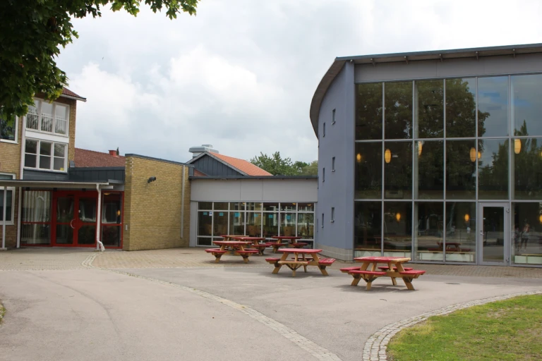 Dackeskolan med asfalterad skolgård med utplacerade bänkar i förgrunden.