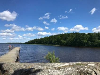 Bild vid Kärrasand. Vatten och brygga och i förgrunden syns berg.