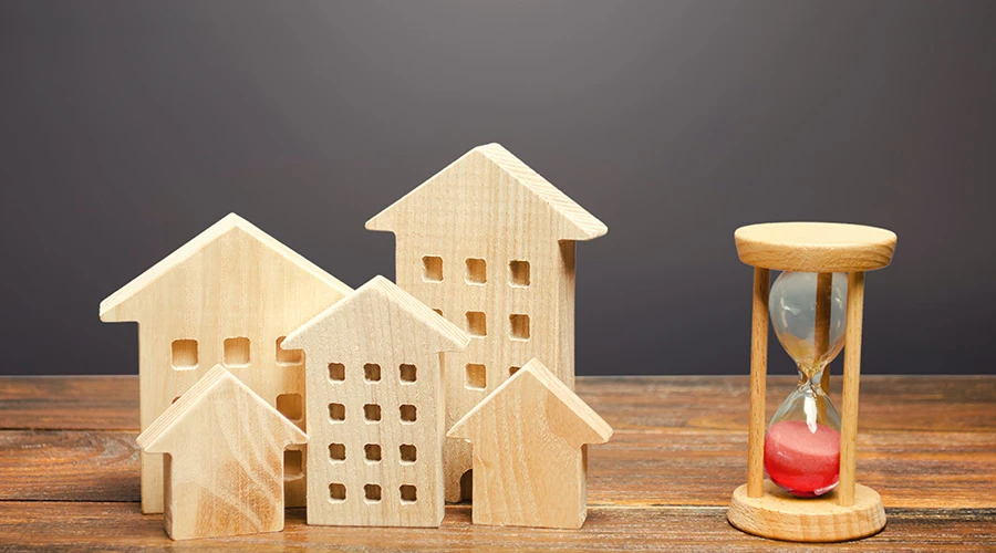 Små trähus på ett bord och ett timglas