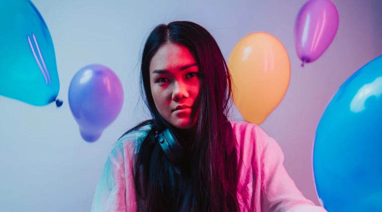 En tjej i förgrunden, bakom sig har hon en grå vägg och ballonger som flyger.