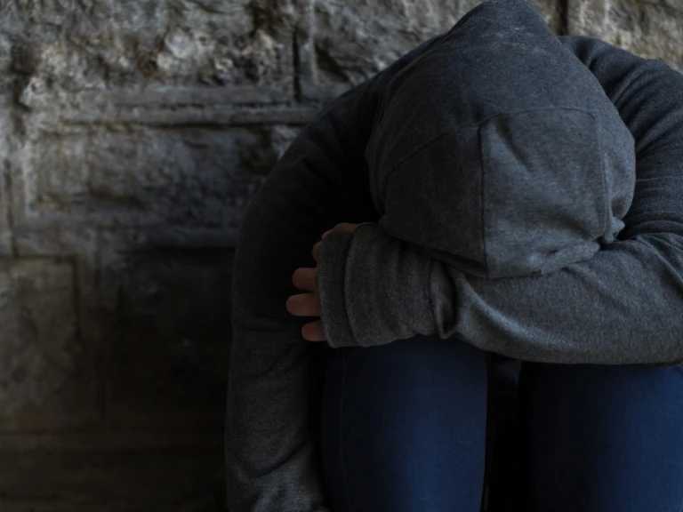 Person sitter hukad med huvtröja