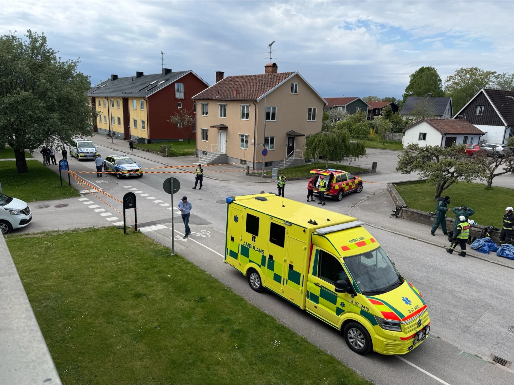 Ambulans, brandbil och polisbilar på avspärrad gata.