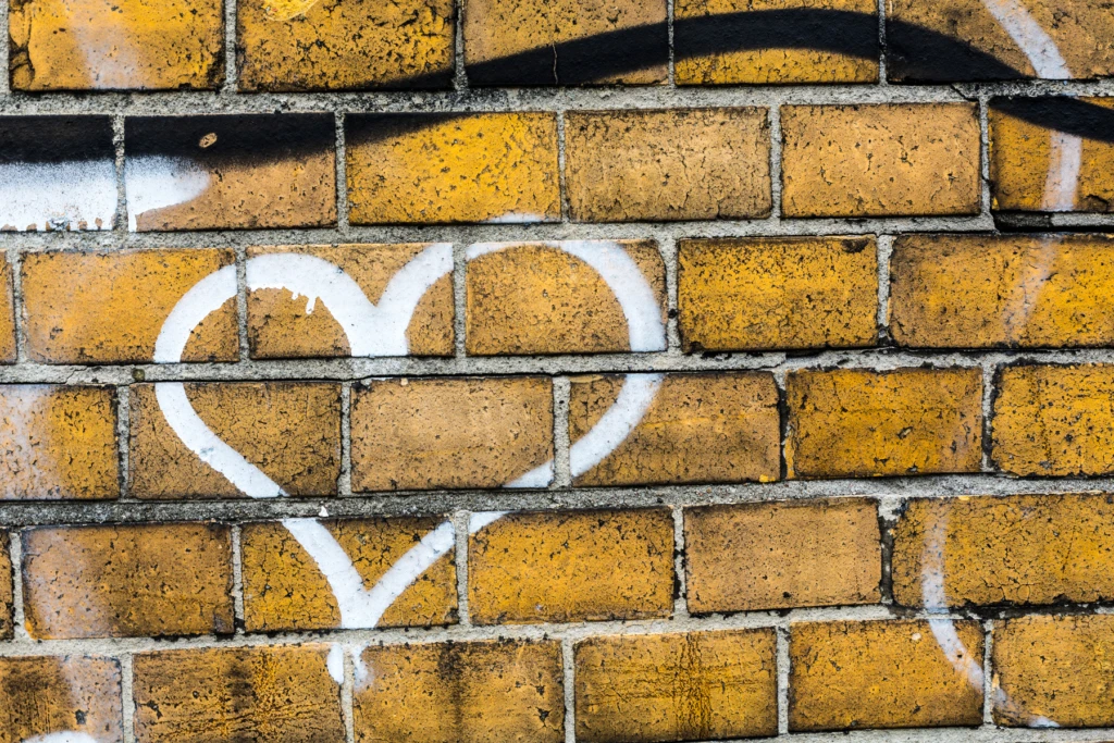 Tegelvägg med vitt hjärta målat i grafitti.