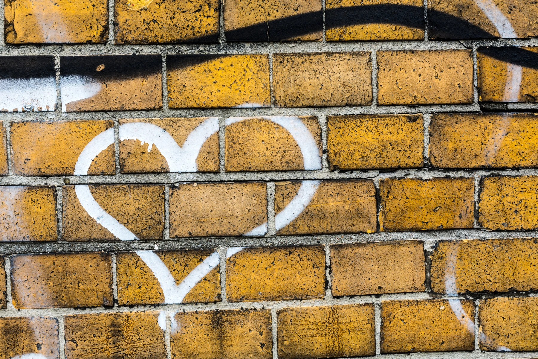 Tegelvägg med vitt hjärta målat i grafitti.