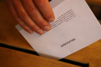 En hand som är på väg att lägga sitt valkuvert i valurnan.