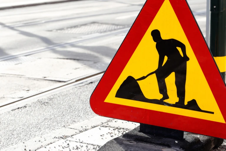 Vägskylt som föreställer triangel i gult med röd ram, person som gräver.